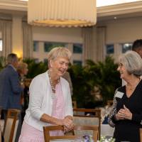 Lydia Tobian and Anita Christopher chatting while standing by their table